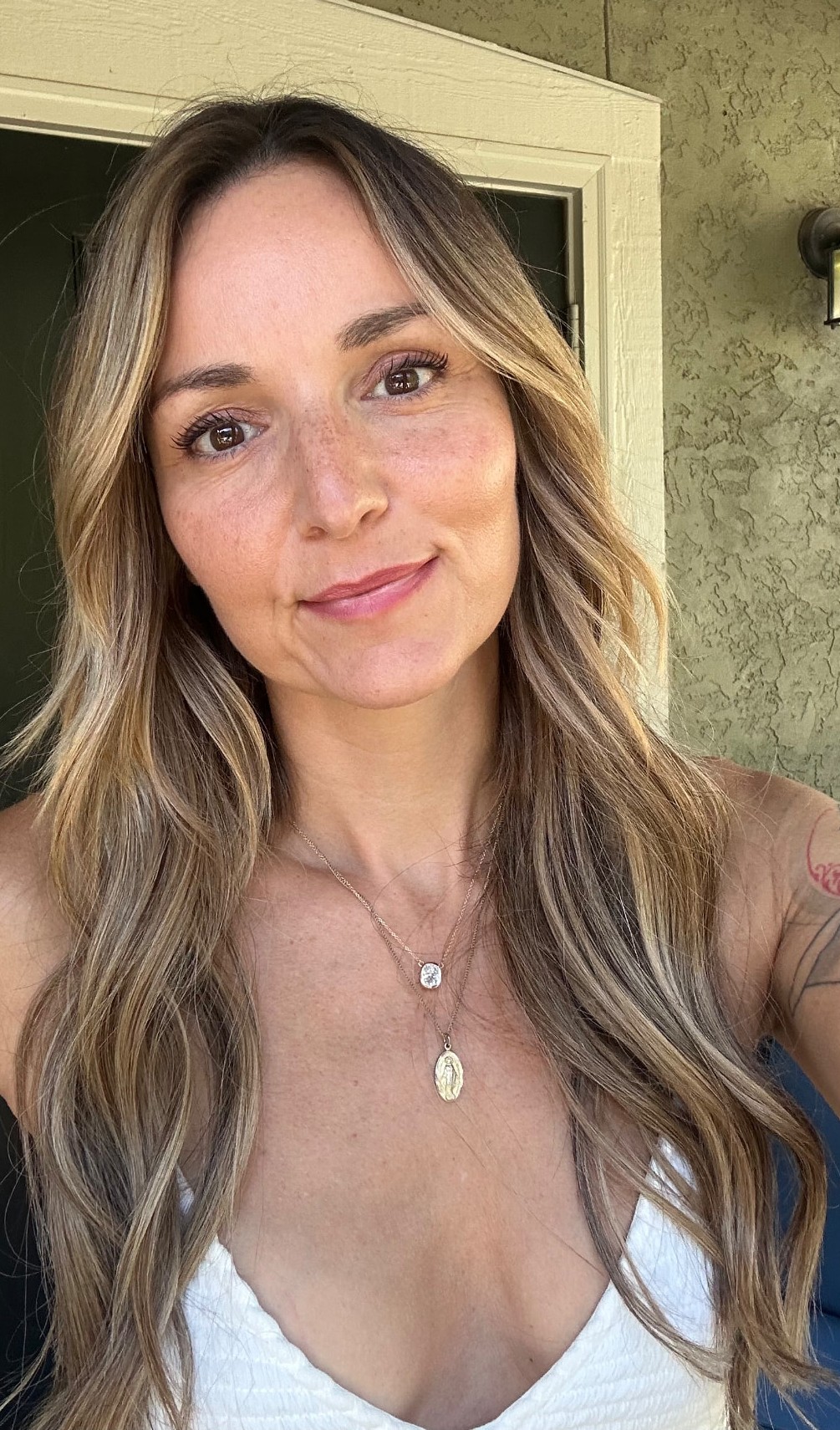 Kayla Watts smiling softly in the sunlight on her porch